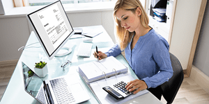 Year-End Checklist For Small Business, business owner reviewing accounting documents at desk