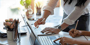 Coworkers working together at a laptop with papers, move to cloud accounting