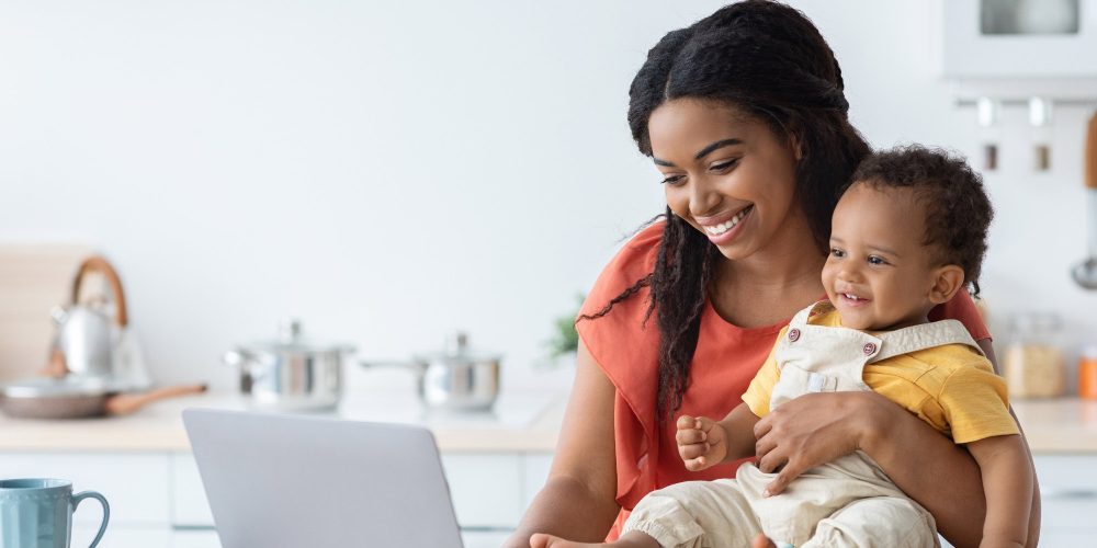 what is a trump account - mom on laptop and holding baby
